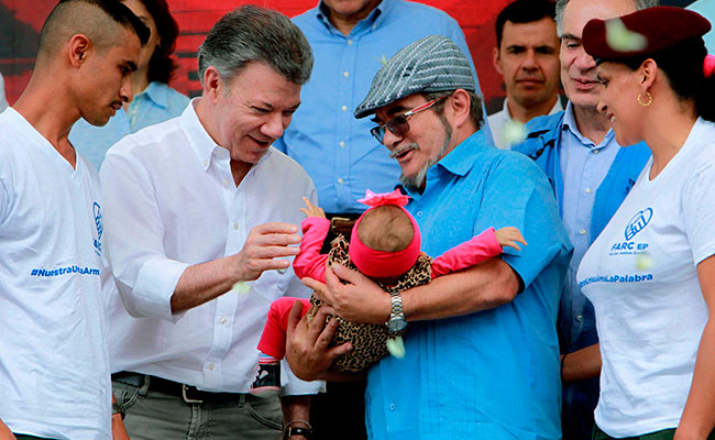El presidente de Colombia, Juan Manuel Santos saluda a una bebé que es sostenida por el máximo líder de las FARC, Rodrigo Londoño, alias Timochenko. Foto: EFE